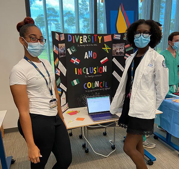 PCOM South Georgia medical students answer questions at a table during a diversity event.