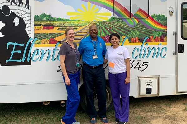 Three people standing in front of a van.