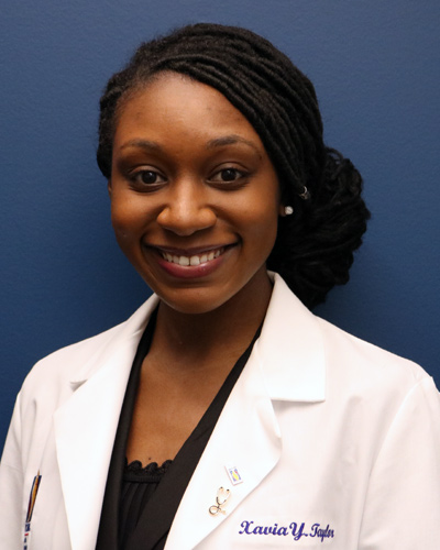 Professional headshot photograph of medical student Xavia Taylor wearing her physician white coat.