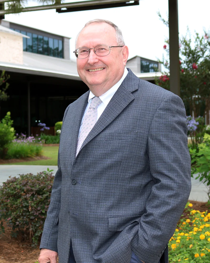 Dr. Robert Lloyd dressed in suit and tie standing outside in PCOM South Georgia's campus courtyard.