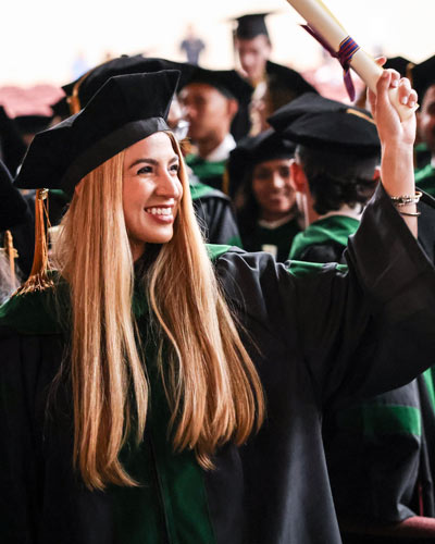 PCOM South Georgia graduate in full regalia raises diploma in celebration