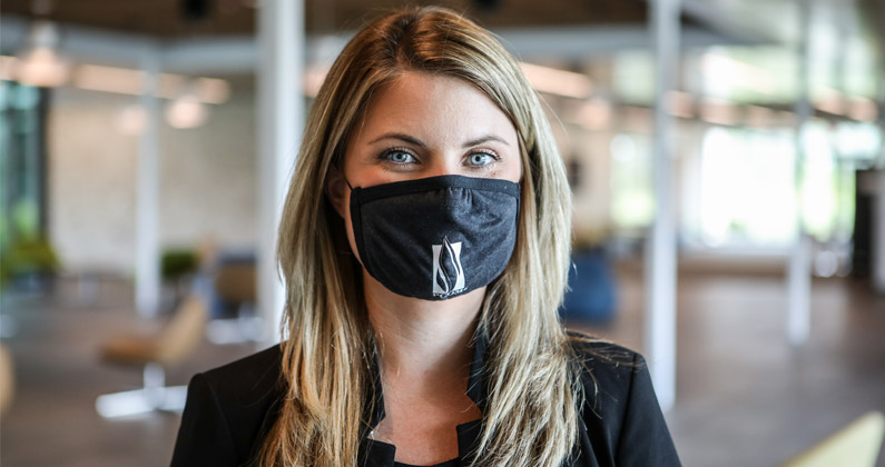 Dana Brooks, assistant director of admissions at PCOM South Georgia, wears a face mask and smiles within the front lobby