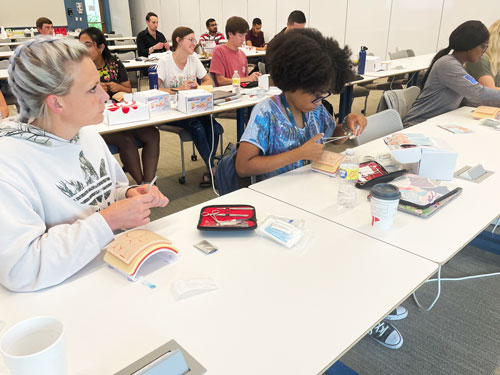 Medical students practice suture techniques in classroom