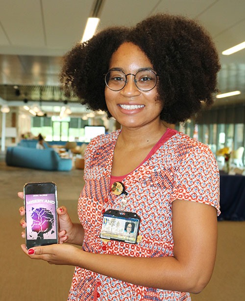 PCOM South Georgia medical student Jada Glenn holds a phone with an image of her mystery book cover