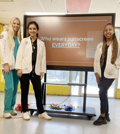 Haley Elliott, Darya Khani and Tiffany Pittman, all second-year medical school students, set up for a recent presentation