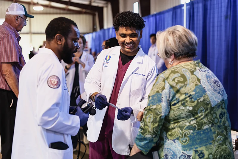 PCOM South Georgia doctoral students assist a visitor at Ag Expo with a health screening