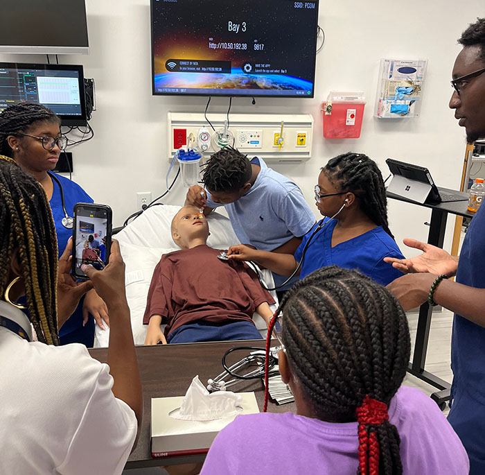 Moultrie area youth take vital signs on a simulation center mannequin under guidance from PCOM South Georgia med students