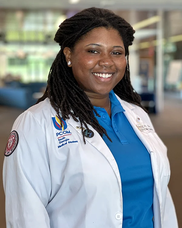 Headshot photo of PCOM South Georgia medical student Melea Neely (DO '29) smiling and wearing her student physician white coat