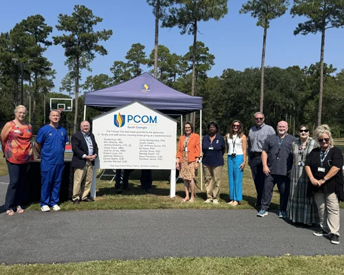 PCOM South Georgia faculty stand outside next to Fitness Trail dedication sign