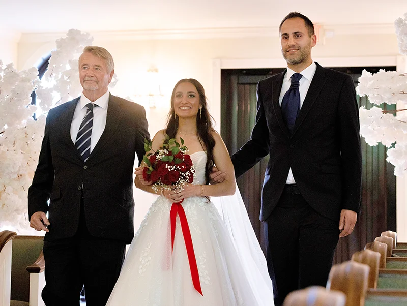 Med student Flora Heydari smiles while walking down the aisle in her wedding dress with her legal guardian