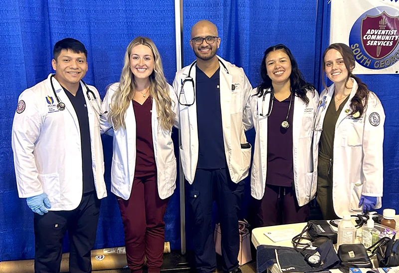 Marisela Benitez (DO '28) and other PCOM South Georgia medical students smile in their white coats at a community service health screening event