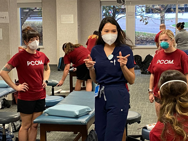 A PCOM OMM Clinical Scholar addresses medical students during a lab.