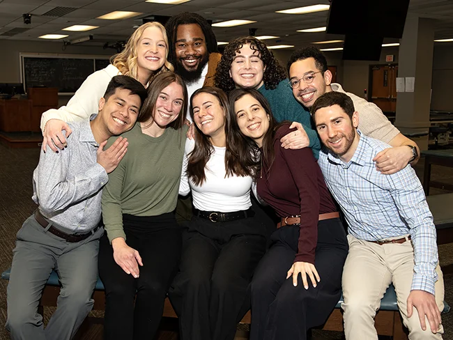 Students from PCOM's OMM Clinical Scholars group smile in a group shot in the OMM lab
