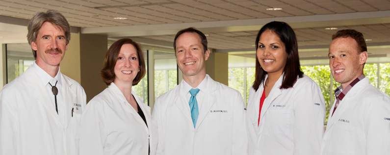 PCOM's OMM physicians stand and smile wearing their white coats
