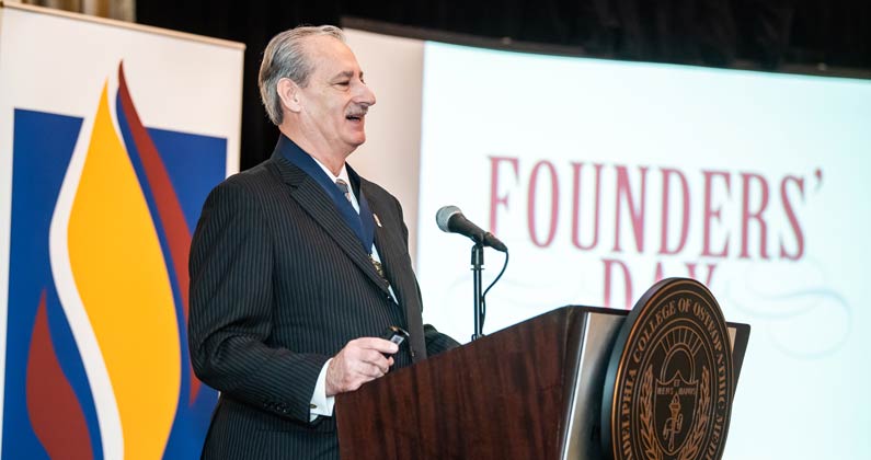 Dr. Alex Nicholas speaks at the podium during the PCOM Founders' Day award ceremony