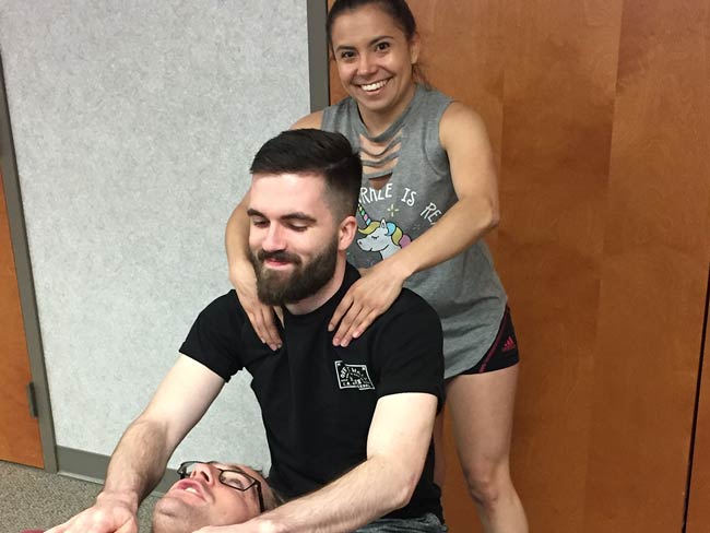 OMM students practicing manipulation on each other in a classroom