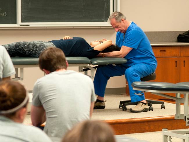 Professor manipulating a student while instructing a class during an OMM lab session