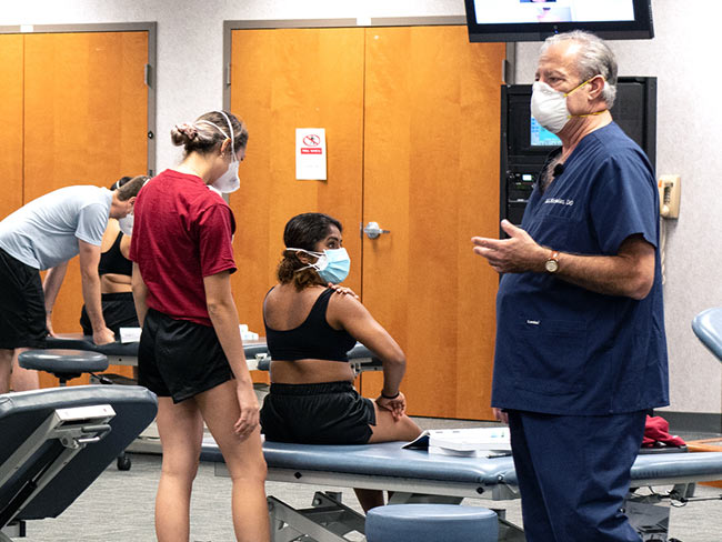 Dr. Nicholas lecturing students during an OMM lab course