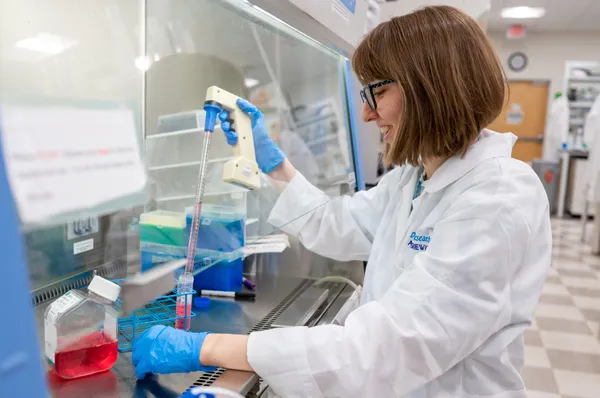A PCOM biomedical sciences student smiles as she works with equipment in a research laboratory
