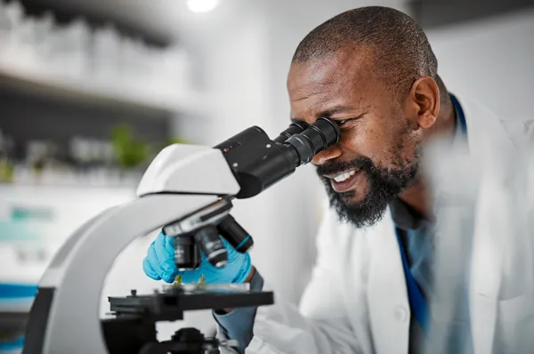 A biomed student smiles as they work with a microscope