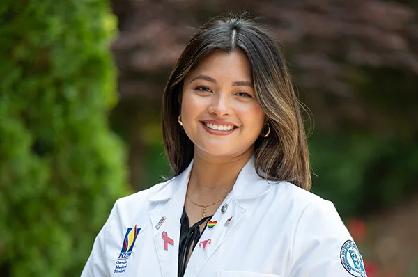 Osteopathic medical student smiling at the entrance of PCOM Georgia in Suwanee