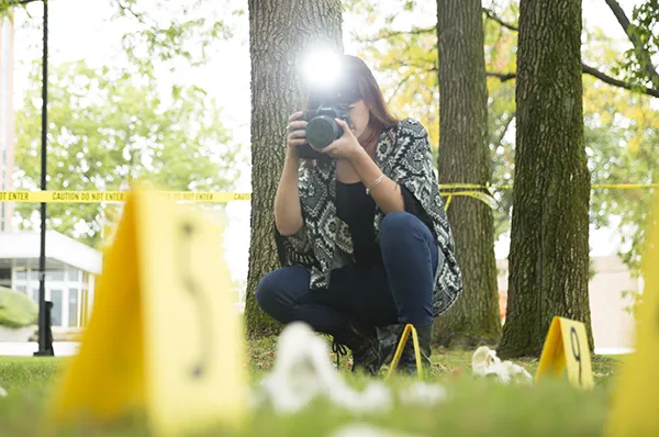 PCOM forensic medicine student taking photographs of a mock crime scene investigation site
