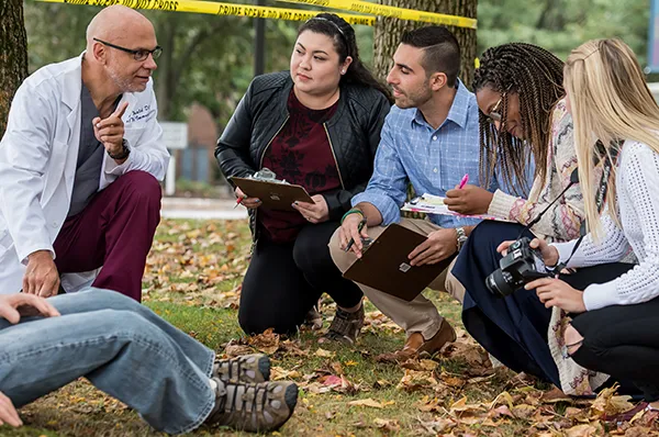 PCOM forensic medicine students and faculty taking notes at a mock crime scene investigation site