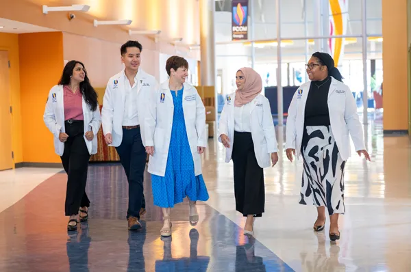 Medical students giving a campus tour to prospective students while they walk and talk inside a hallway at PCOM Georgia