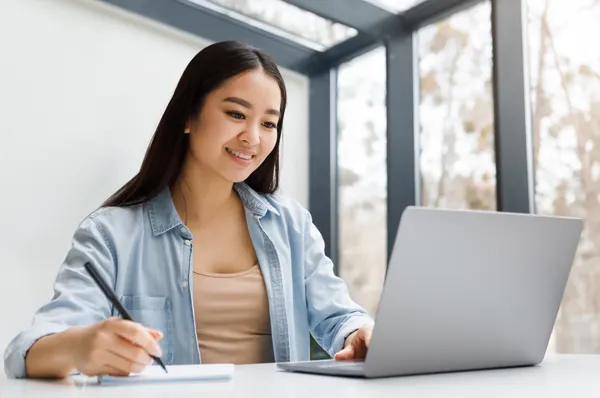 A grad student taking notes while attending PCOM's Social Media and Mental Health Virtual Workshop on her laptop