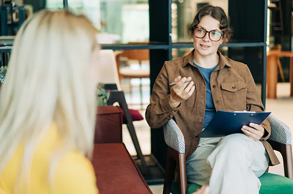 Mental health counselor sits in chair and talks to patient