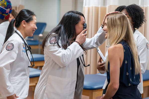 Physician assistant students smile as they conduct patient exam exercises at PCOM Georgia
