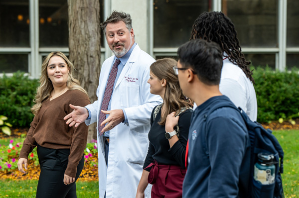 PCOM Doctor of Osteopathic Medicine students walk across campus with Dr. Peter Bidey