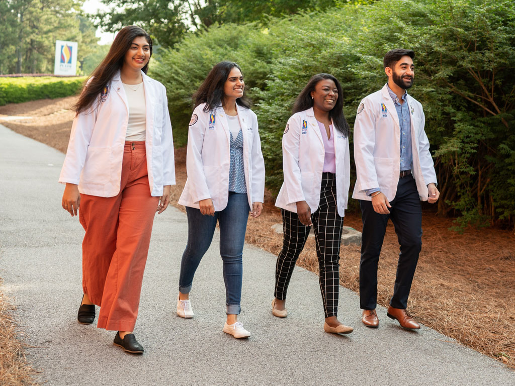 Medical students walk and talk on a path outside of the PCOM Georgia Suwanee campus