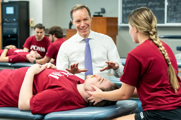 PCOM OMM faculty member teaching Still Technique to medical students