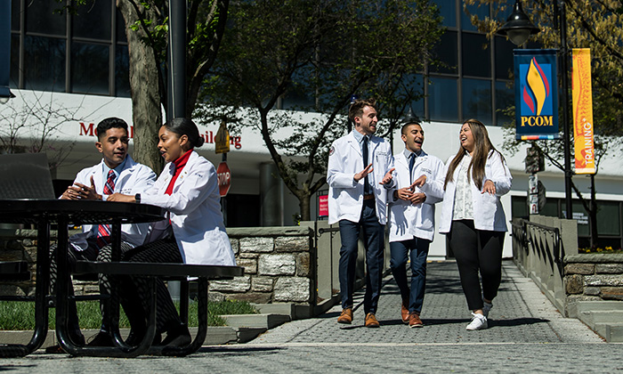 PCOM students walking and talking on a pathway during a campus tour.