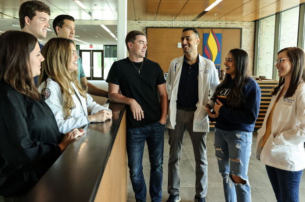 PCOM South Georgia students smile and talk in the main lobby while giving a campus tour to visitors