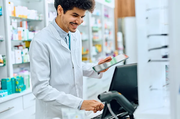 A PCOM pharmacy student smiles while using a computer and tablet in a lab