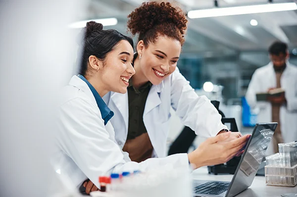 PCOM Georgia pharmacy students smile while looking at a laptop in a laboratory exercise