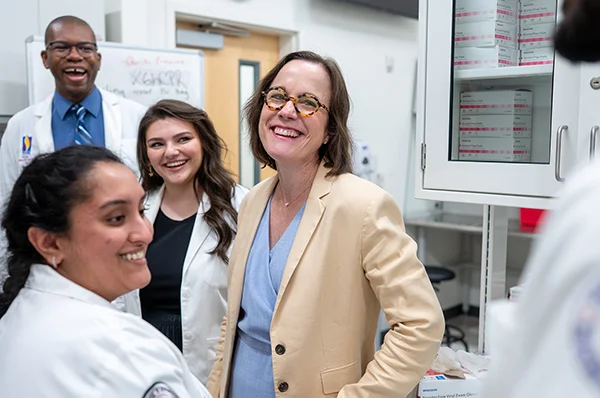 PCOM Georgia faculty, students and visitors smile and laugh in a lab during a Pharmacy program admissions event