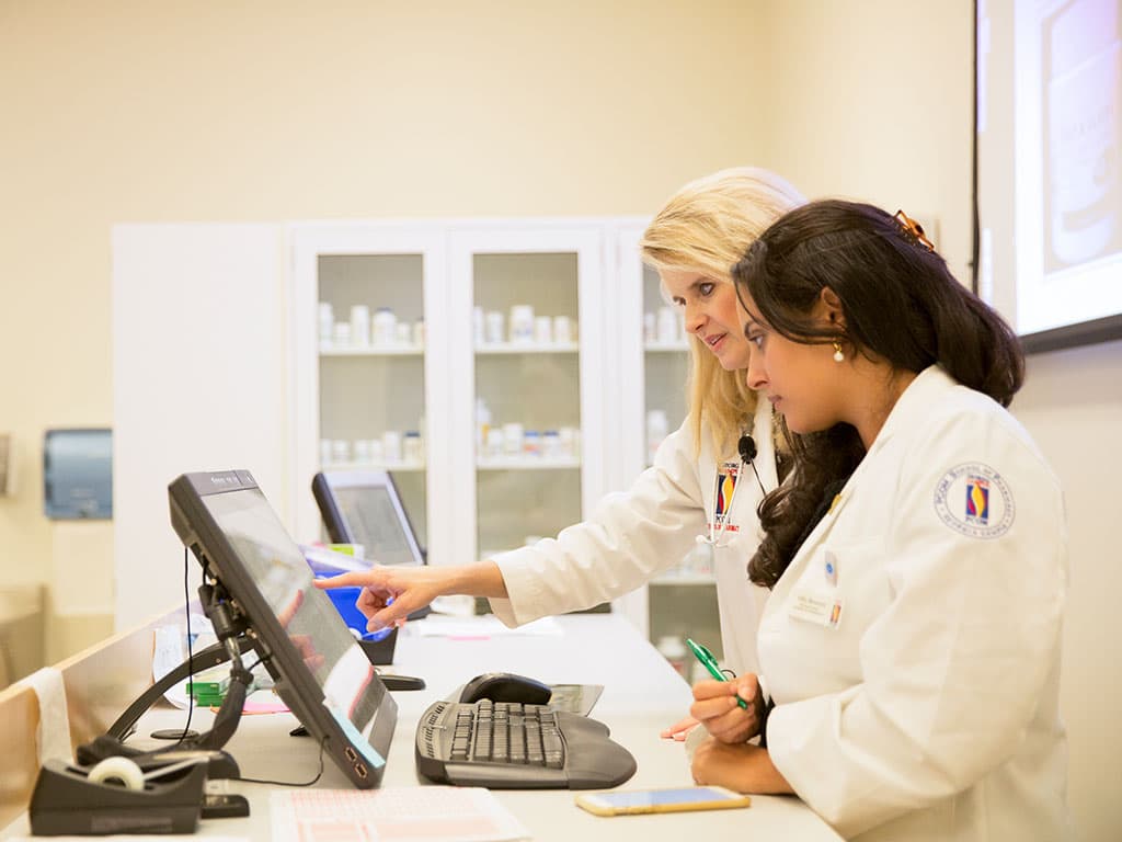 Pharmacists consult at a computer screen