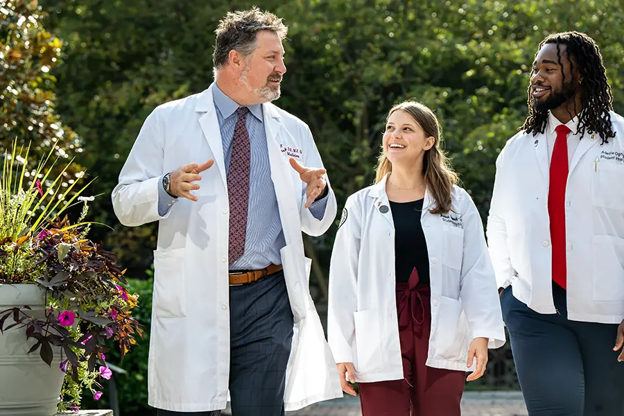Medical students and faculty walking and smiling while giving a tour to prospective PCOM students.