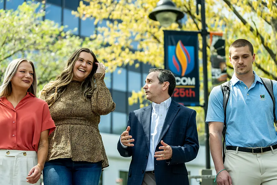 PCOM students and faculty talking while strolling on a walkway during a campus tour.