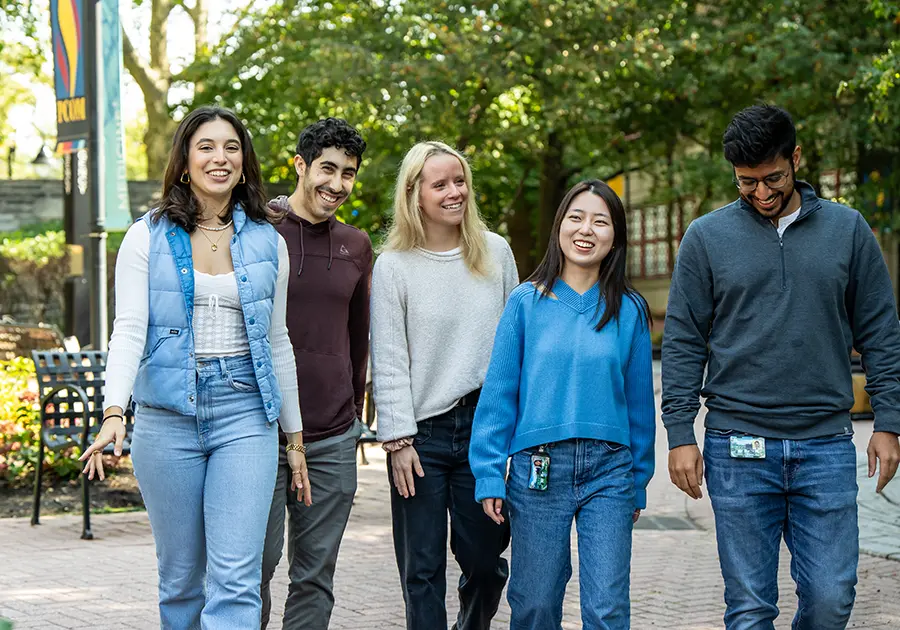 PCOM students walking and smiling as they give a campus tour to visitors.