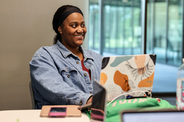 One-year master's student smiling and studying in a PCOM laptop