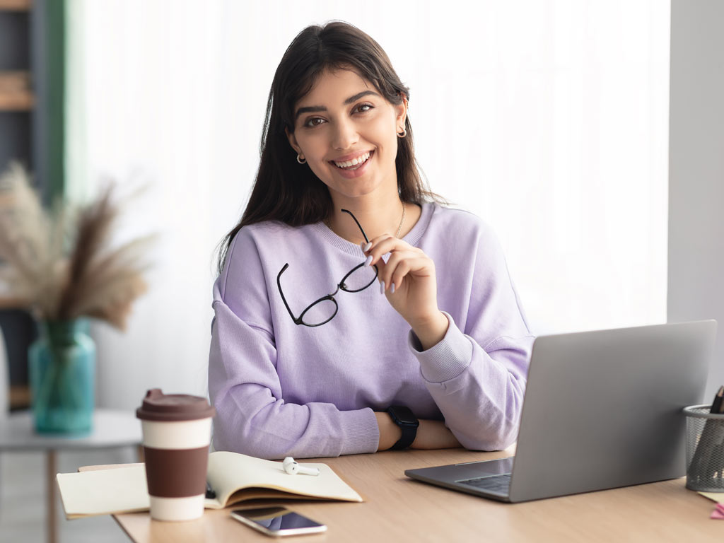 PCOM Positive Psychology student sitting at desk with laptop computer