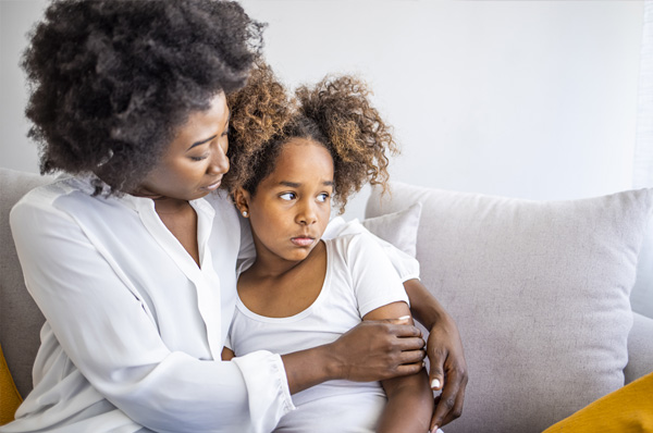 Mother hugging a stressed child on a couch