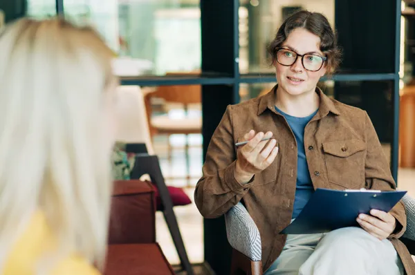 Psychologist sits and talks to patient while taking notes