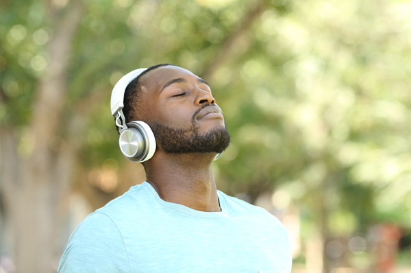 Young man wearing headphones breathing deeply with closed eyes