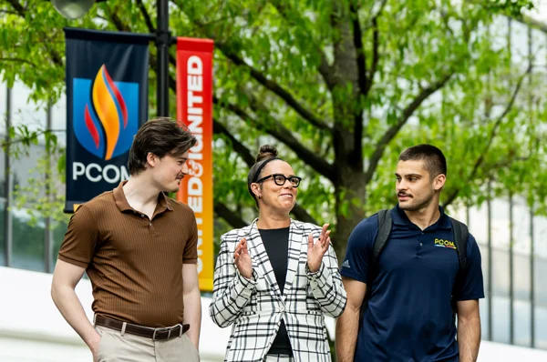 PCOM psychology students and faculty walk and talk outside with guests during a campus tour event