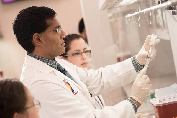 Dr. Samuel John, director of the PGY-1 Residency Program at PCOM School of Pharmacy, instructs a student in the pharmacy lab.